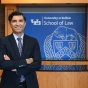 man standing in front of a sign that says University at Buffalo School of Law. 