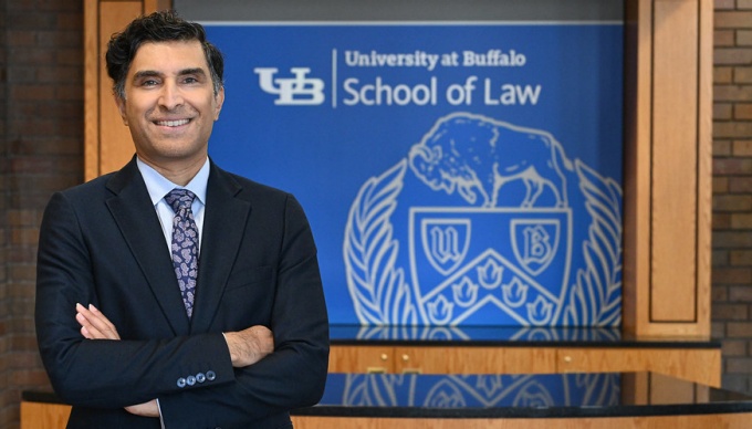 man standing in front of a sign that says University at Buffalo School of Law. 