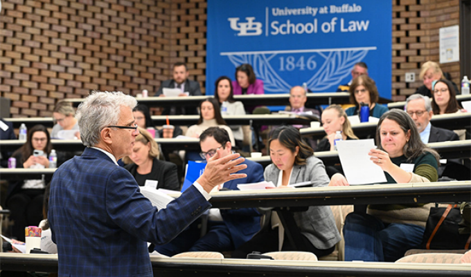 Man addressing a classroom of people. 