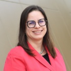 A woman wearing glasses, smiling. 