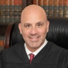 Man wearing judges robe inside a library. 