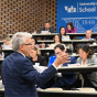 Man addresses a large classroom of people. 