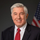 man standing in front of U.S. flag.