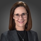 woman wearing glasses, smiling.