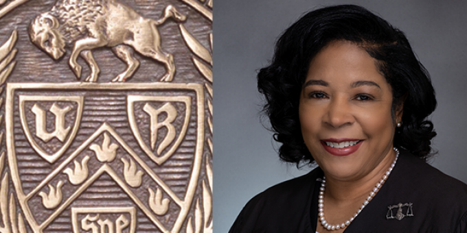 Photo of woman smiling next to a bronze academic seal. 