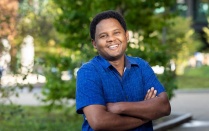 Man standing outside, smiling, arms crossed. 