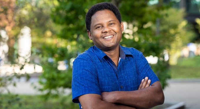 Man standing outside, smiling, arms crossed. 