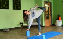 young woman, smiling, demonstrating a yoga position. 