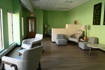 Zoom image: View of a room with grey furniture, green walls and large windows.