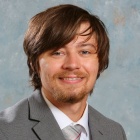 Young man wearing a suit, smiling. 