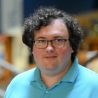 Man wearing blue shirt, glasses, standing inside the main entrance of the law library.