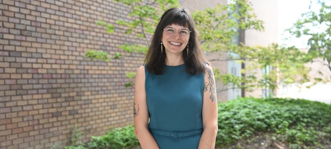 Lauren Wilson stands outside next to O'Brian hall, smiling.