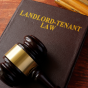 View of a table with a judge's gavel laying on a book that says "landlord-tenant law.". 