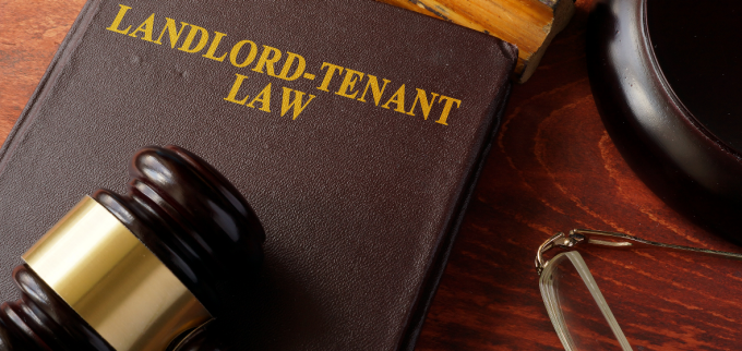 View of a table with a judge's gavel laying on a book that says "landlord-tenant law.". 