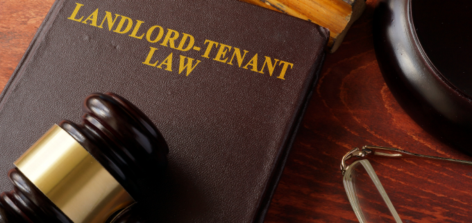 View of a table with a judge's gavel laying on a book that says "landlord-tenant law.".