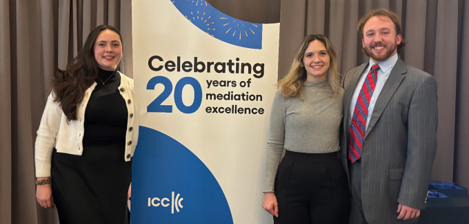 Two women, one man, standing next to a sign that says Celebrating 20 Years of Mediation Excellence. 