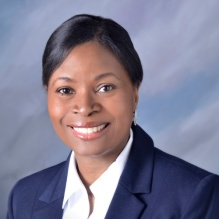 Woman wearing blue blazer, white shirt, smiling.