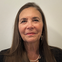 Woman wearing pearl necklace, smiling.