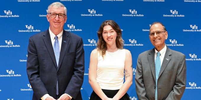 Three people, standing in front of a UB University at Buffalo screen, smiling.