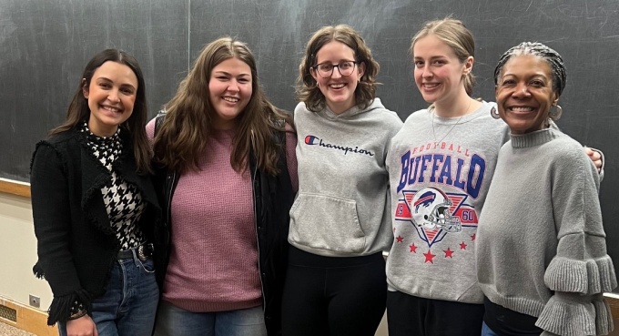 Five women standing in front of a large blackboard. 