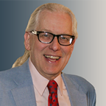 Prof. Schlegel wearing blue suit, red tie, smiling.