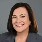 Patricia Ciccarelli smiling, wearing grey jacket, black top and gold necklace.