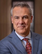 Man wearing blue suit, red tie, smiling. 