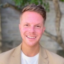 Man standing outside, smiling. 