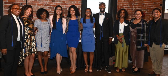 A group of young adults standing together in a line, smiling. 