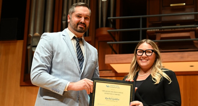 woman and young man standing, man holding an awards plaque. 