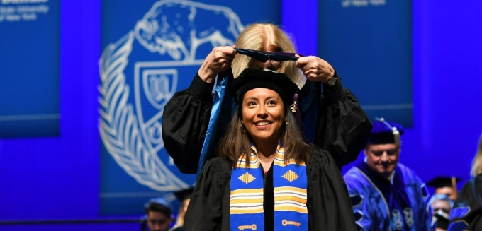 graduate receiving her hood during a commencement ceremony.