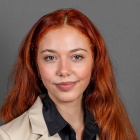 Eve Albert ’27 wearing beige jacket, smiling.