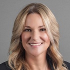 Rachael Cunningham wearing grey jacket, gold necklace, smiling.