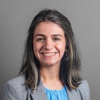 Sarah Jiva wearing grey jacket, blue top, smiling.