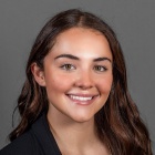 Sarah Isabelle Sauer wearing black jacket, brown top and gold necklace.