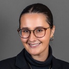 Sandy Sparks wearing black jacket, gold necklace and glasses.